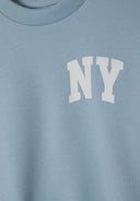 Detail of a blue crew neck sweatshirt featuring a white 'NY' print.