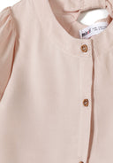 Detail of a pink blouse with flared sleeves and button fastening at the back.