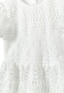 Detail of a girls' white flare sleeve dress with lace detailing.