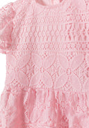 Detail of a pink girls dress with flared sleeves and lace pattern.