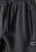 Detail of boys' grey joggers featuring elastic waistband and side pockets.