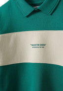 Close-up of boys fleece polo jumper in green with contrasting beige panel and decorative patch.