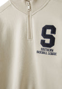 Close-up of boys half zip jumper in cream with ribbed collar and embroidered logo.