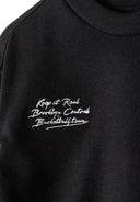 Detail of a black boys' sweatshirt featuring a graphic print and ribbed neckline.