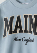 Close-up of boys light blue fleece crew neck sweatshirt with printed text.