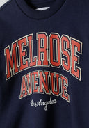 Close-up of a navy boys fleece crew neck sweatshirt featuring a decorative print.