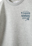 Detail of a grey boys t-shirt featuring a tennis print on the chest.