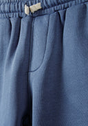 Detail of blue shorts with elasticated waistband and side pockets.