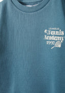 Detail of a green short sleeve t-shirt with tennis print.