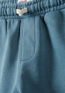 Detail of green shorts with elasticated waistband and side pocket.