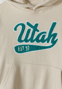 Detail of a cream oversized boys hoodie with kangaroo pocket and decorative print.