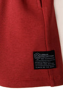 Detail of boys fleece shorts in red with ribbed side panels and logo patch.