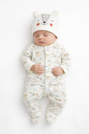 Sleeping baby in a cream cotton sleepsuit with animal prints and a cute bear hat showcasing soft kids fashion design.