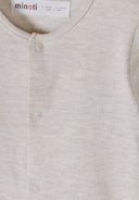 Close-up of a soft neutral beige baby sleepsuit with a snap button design for easy dressing and comfort.