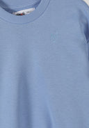 Light blue girls sweatshirt with a small embroidered heart design near the neckline in kids fashion style.