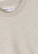 Close-up of a cream cotton sweatshirt with ribbed collar and subtle heart embroidery design for kids fashion.