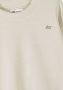 Close-up of cream sweatshirt with small embroidered animal detail, soft fabric, and ribbed neckline in kids fashion design.