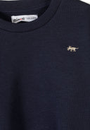 Close-up of navy cotton sweatshirt with small embroidered animal detail and ribbed neckline for boys' fashion.