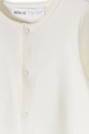 Close-up of soft white baby sleepsuit with snap button design for easy dressing and comfort