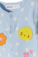 Close-up of light blue cotton sleepsuit with white polka dots and cheerful sun and flower embroidery design