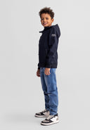 Boy wearing a black softshell jacket with hood and jeans, showcasing a stylish and functional kids fashion design.