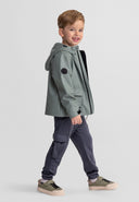 Boys waterproof teal parka with adjustable hood, front view, featuring a logo badge.
