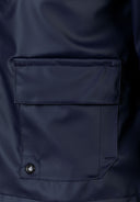 Detail of a navy blue boys' parka jacket showing a zippered chest pocket.