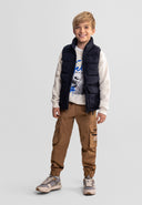 Smiling boy wearing a black quilted nylon waistcoat with stand collar and flap pockets in a casual outfit