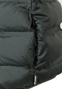 Detail of a boys' quilted sleeveless waistcoat in olive with padded insulation and logo tag.