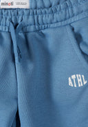 Close-up of blue boys joggers with elastic waistband, drawstring, side pockets, and sporty ATHL design detail.