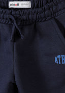 Close-up of navy blue boys joggers with elastic waistband, drawstring, side pockets, and partial athletic logo design.