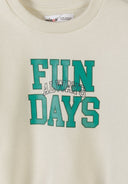 Close-up of cream kids sweatshirt with green sports-themed "FUN ALWAYS DAYS" print design on front