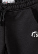 Close-up of black boys joggers with elastic waistband, drawstring, side pocket, and white athletic print detail