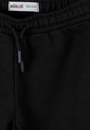 Close-up of black joggers waistband with drawstring and elastic band showing detailed fabric texture and design.