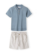Light blue knitted polo shirt with beige shorts set, front view, features buttons and elastic waistband.