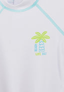 Close-up of white kids rash set top with lime and blue palm tree design and contrast stitching