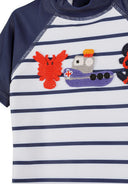 Close-up of boys short sleeve marine striped rash suit with nautical-themed crochet patches on the chest area.