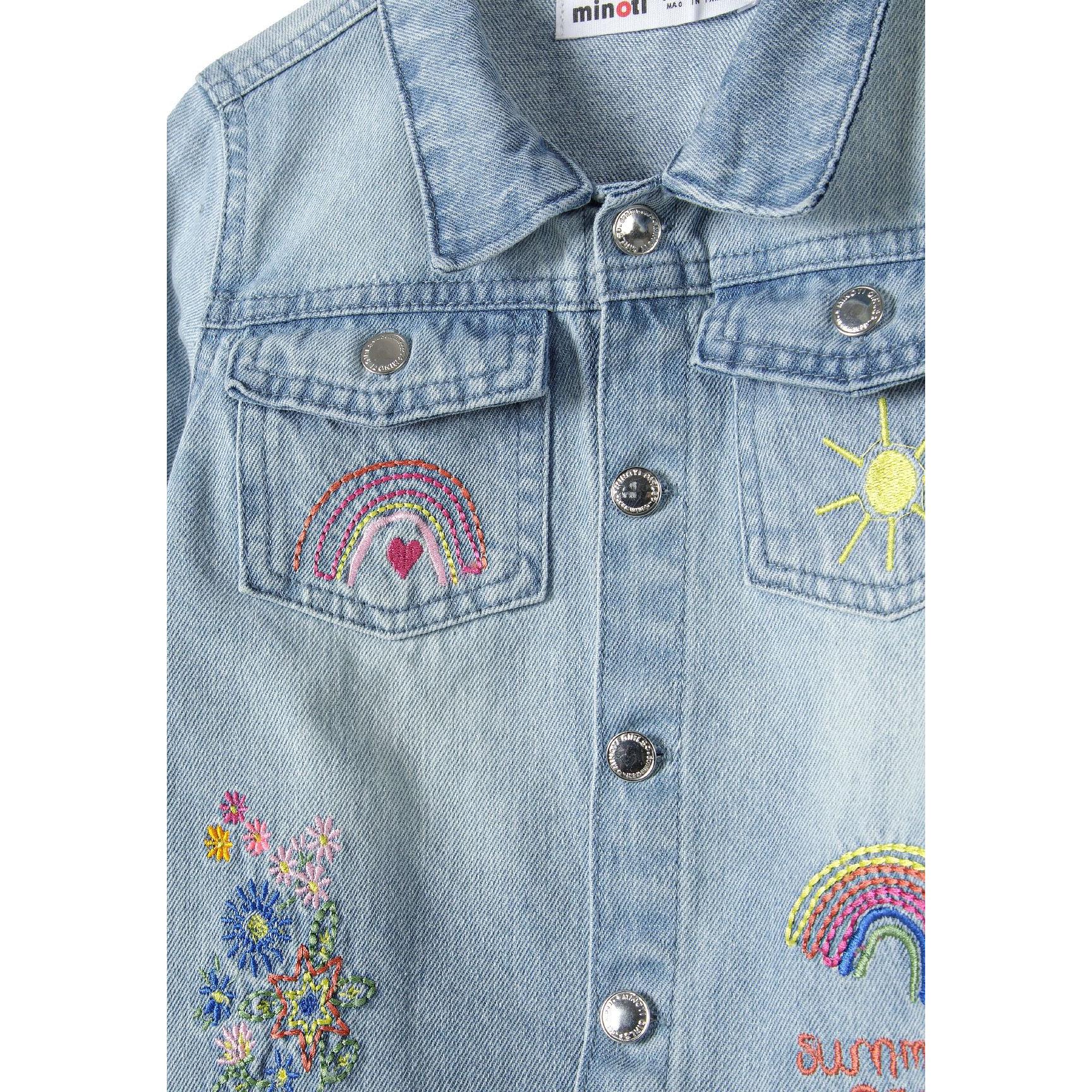 Close-up detail of light blue denim jacket showing embroidered rainbow, sun and floral motifs with button closure