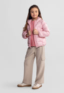 Young girl wearing a stylish pink hooded jacket with a lightweight nylon design standing confidently against a neutral background