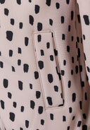 Detail of a girls' softshell jacket in pink with black spots, featuring a front pocket.