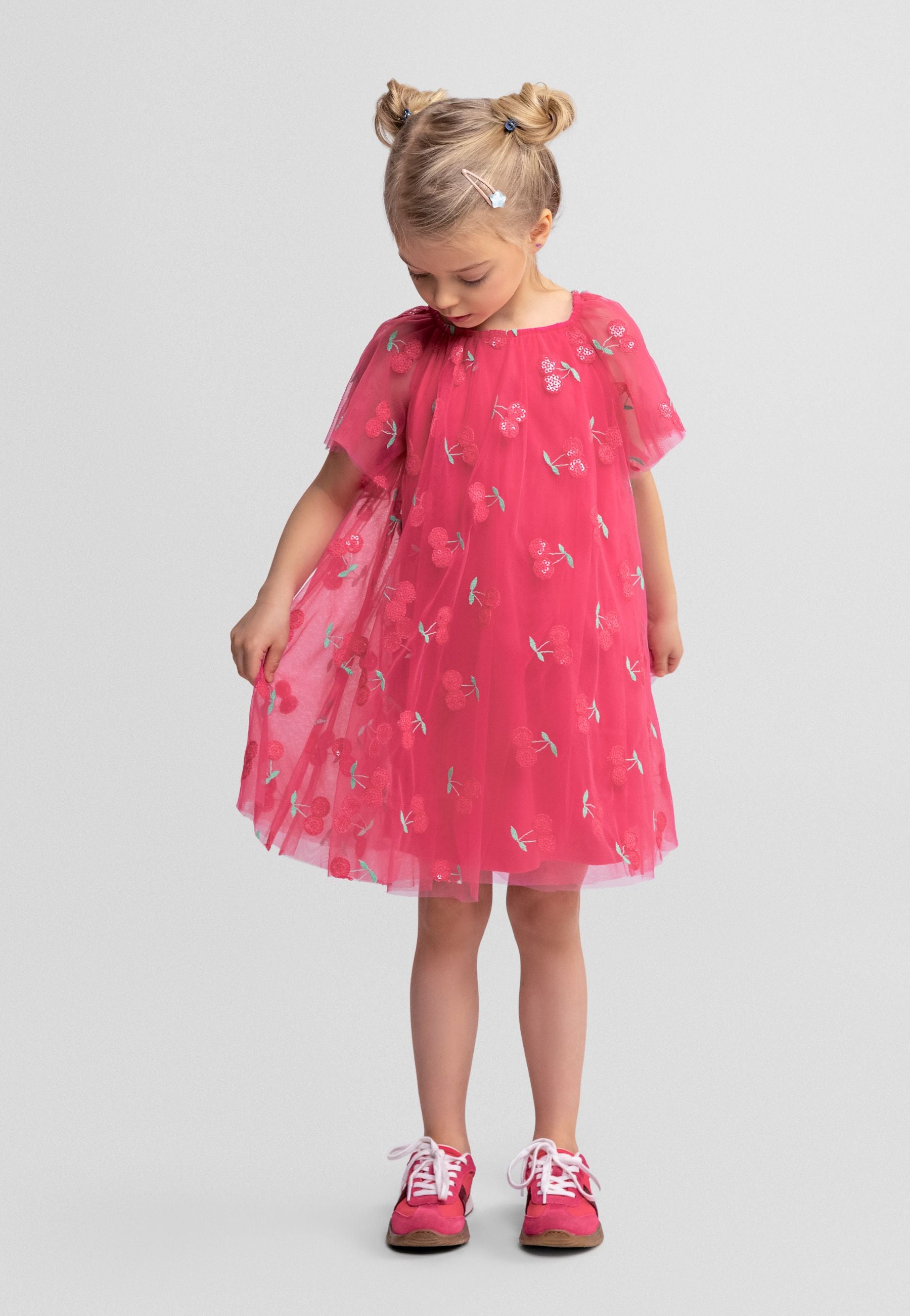 Pink tulle dress laid flat showing layered construction, angel sleeves, and sequin cherry embellishment pattern on white background