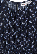 Close-up of blue floral fabric with delicate white and light blue flowers and textured design detailing.
