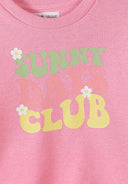 Close-up of pink kids sweatshirt with colorful "Sunny Days Club" text and floral design, showcasing unique style.