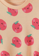 Close-up of apricot fabric with cute smiling apple faces print on kids sweatshirt design
