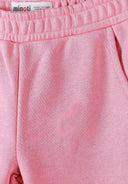 Close-up of coral pink girls joggers with elastic waistband and side pocket, showing soft fabric texture and design details.