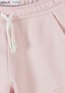 Close-up of pink girls joggers with elastic waistband, white drawstring, and soft cotton fabric showcasing design details.
