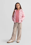 Girl wearing beige wide leg joggers with cargo pockets and a pink padded jacket, standing confidently in casual outfit design.