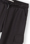 Close-up of black wide leg joggers featuring elasticated waist and combat pocket design for girls.
