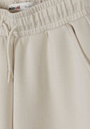 Close-up of beige wide leg joggers with adjustable waistband and side pocket detail in soft fabric design