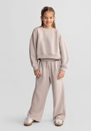 Young girl smiling wearing beige wide leg joggers with adjustable waist and casual sweatshirt.